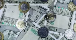 Top view of various Indian rupee banknotes and coins, highlighting financial themes.