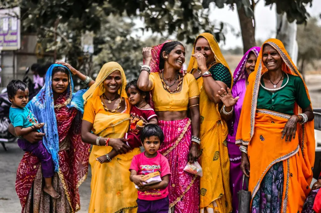 A lively group of women and children in traditional Rajasthani attire, showcasing vibrant culture and joyful expressions.
